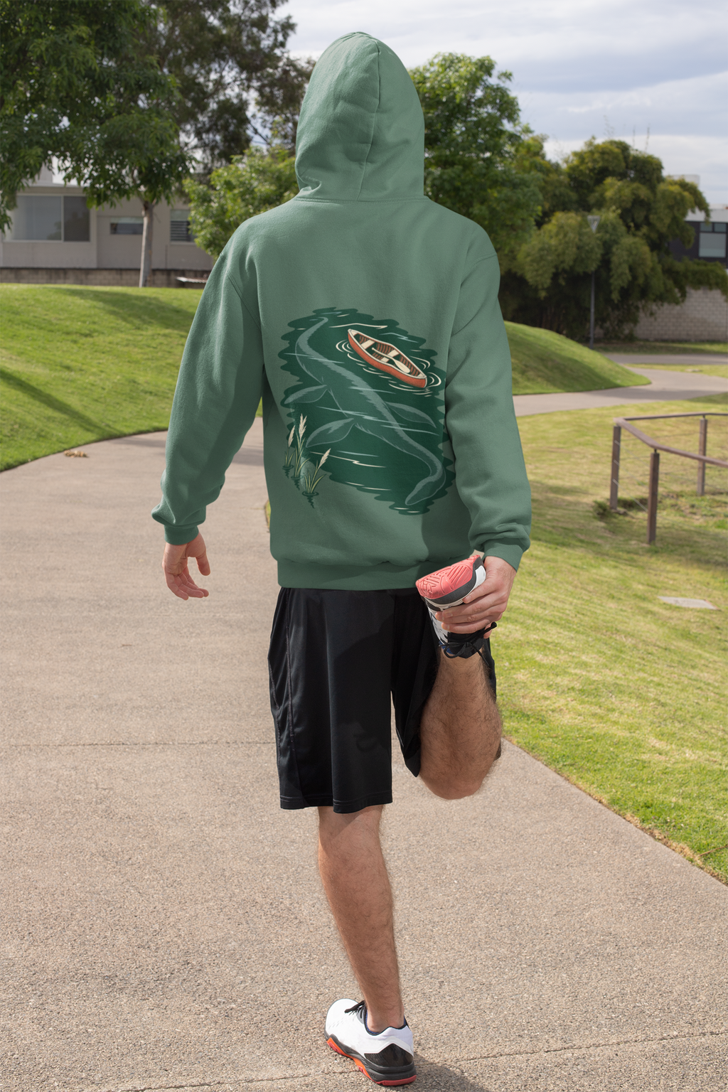 Seen Briefly Midweight Hoodie in Alpine Green, worn by a man seen from behind on a sunny path, ready for a run, showing the large print on the back. Digital product mockup.