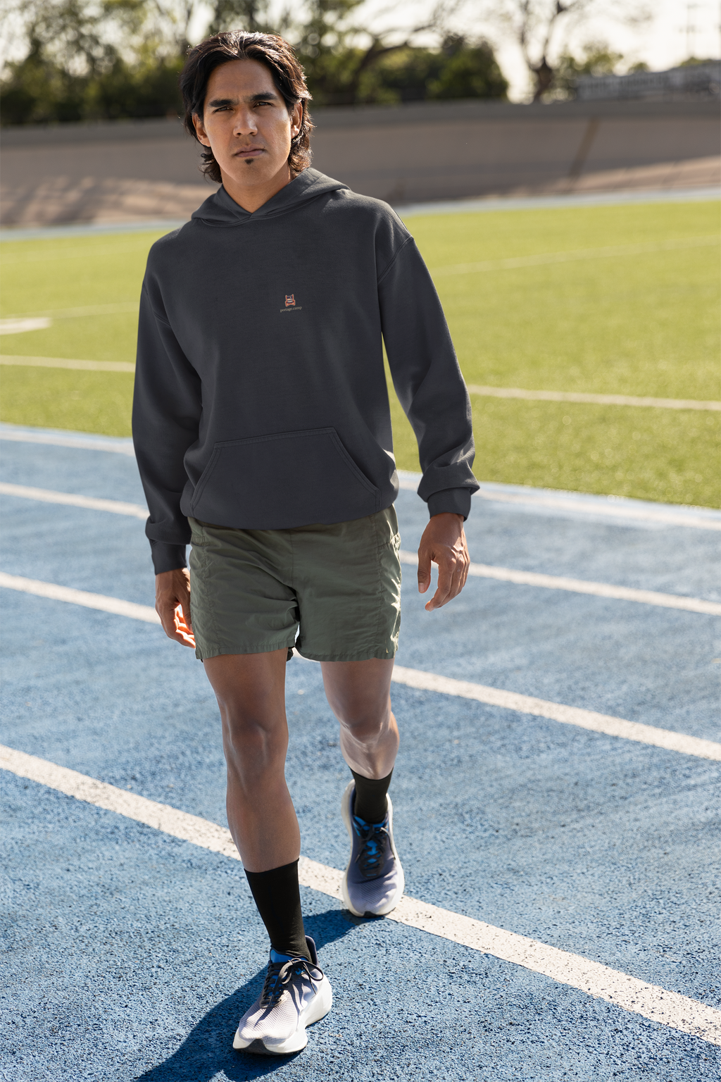 Edge of Evening Midweight Hoodie in Classic Navy, worn by a man on a running track, with the Edge of Evening logo and portage.camp on the chest. Digital product mockup.