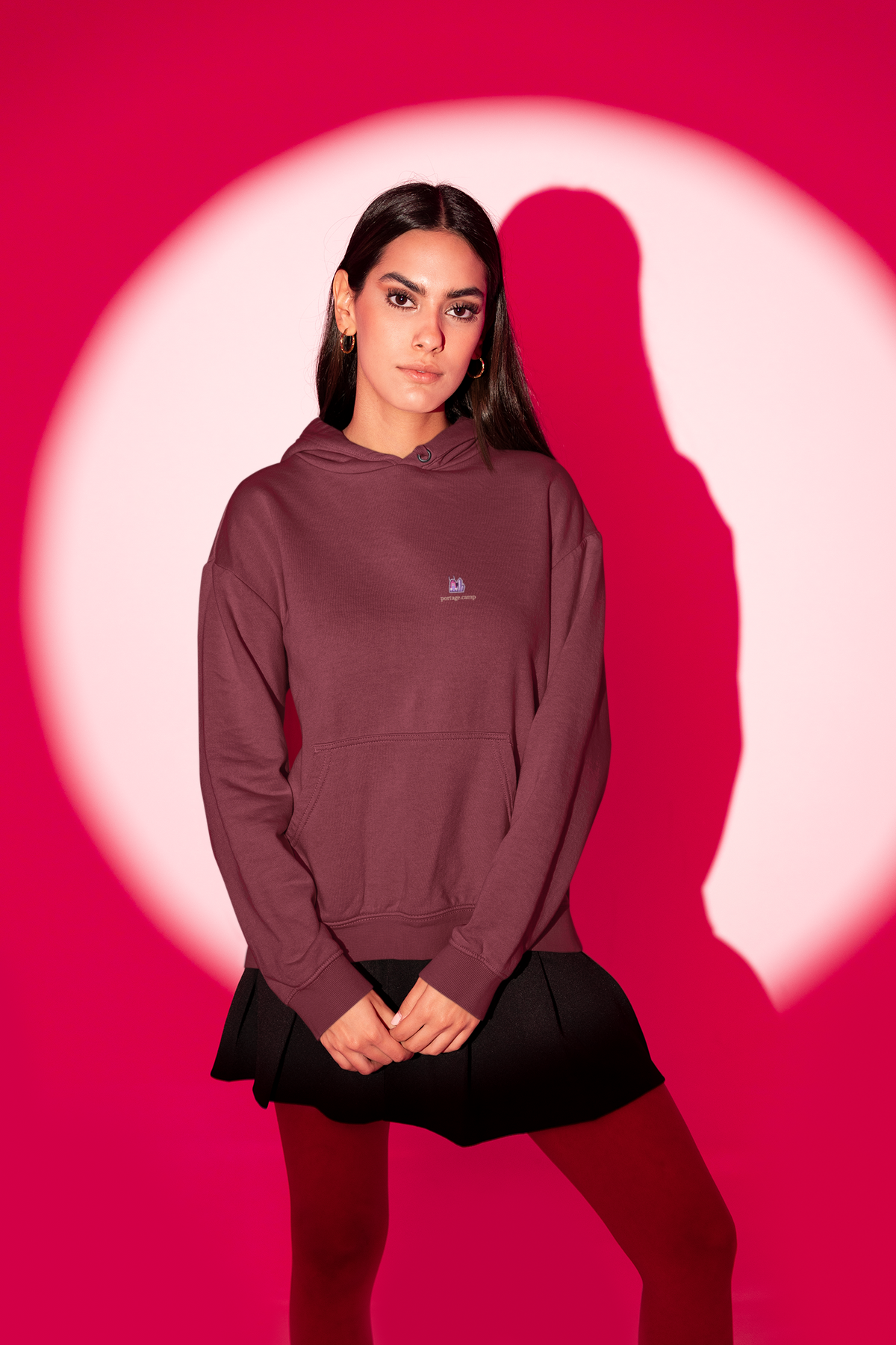 Amethyst After Hours Midweight Hoodie in Maroon, worn by a woman in a red-lit studio, with the Amethyst After Hours logo and portage.camp on the chest. Digital product mockup.