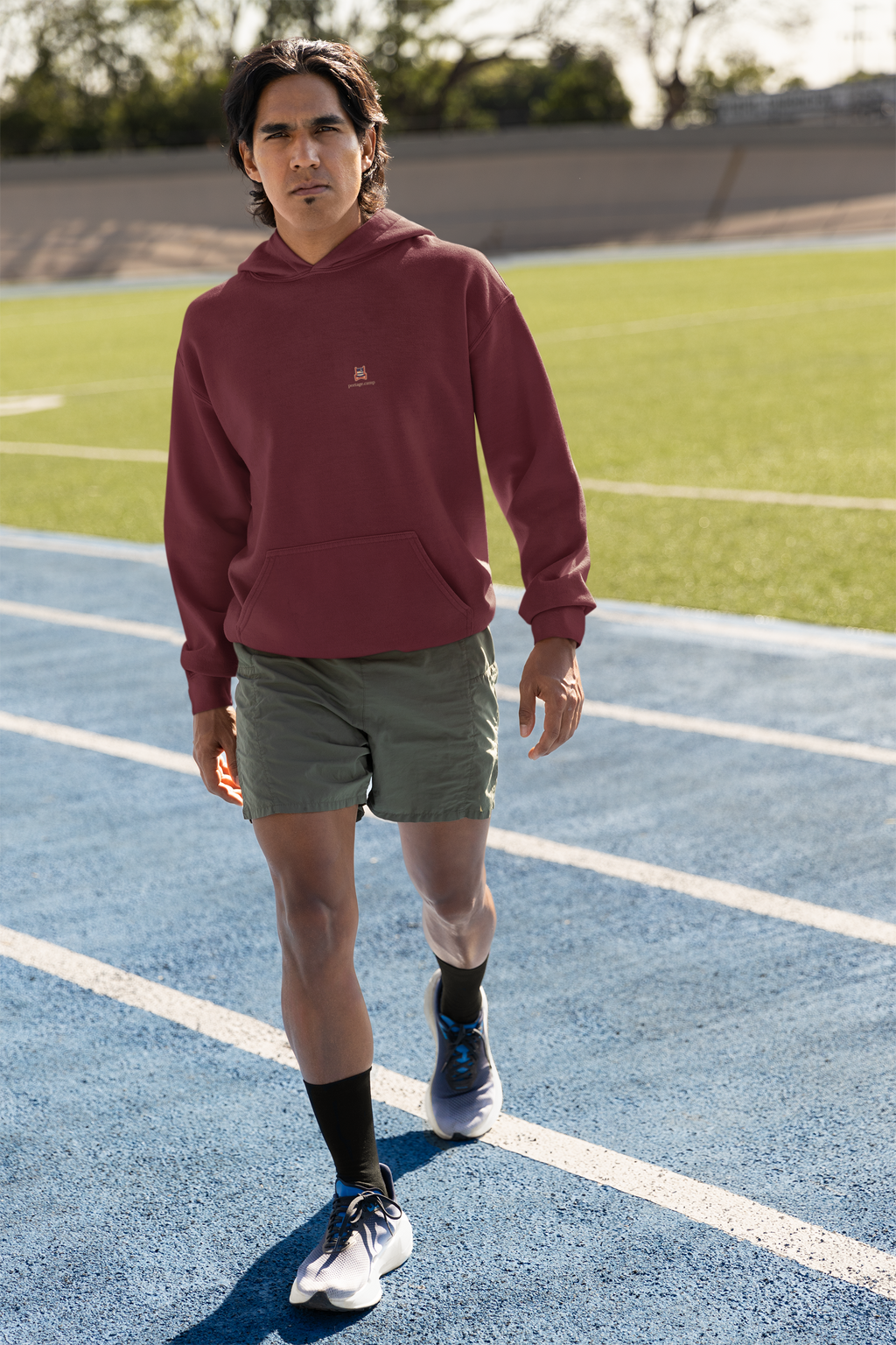 Edge of Evening Midweight Hoodie in Maroon, worn by a man on a running track, with the Edge of Evening logo and portage.camp on the chest. Digital product mockup.