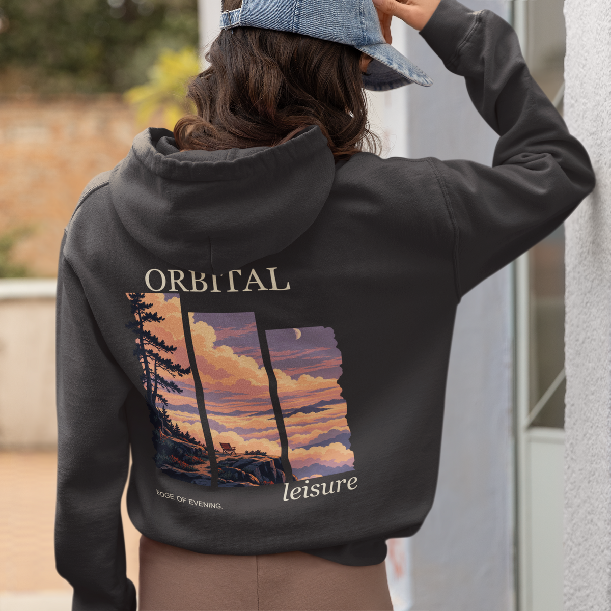 A Different Sky Heavyweight Hoodie in Black, worn by a woman seen from behind at home, showing the large print on the back. Digital product mockup.