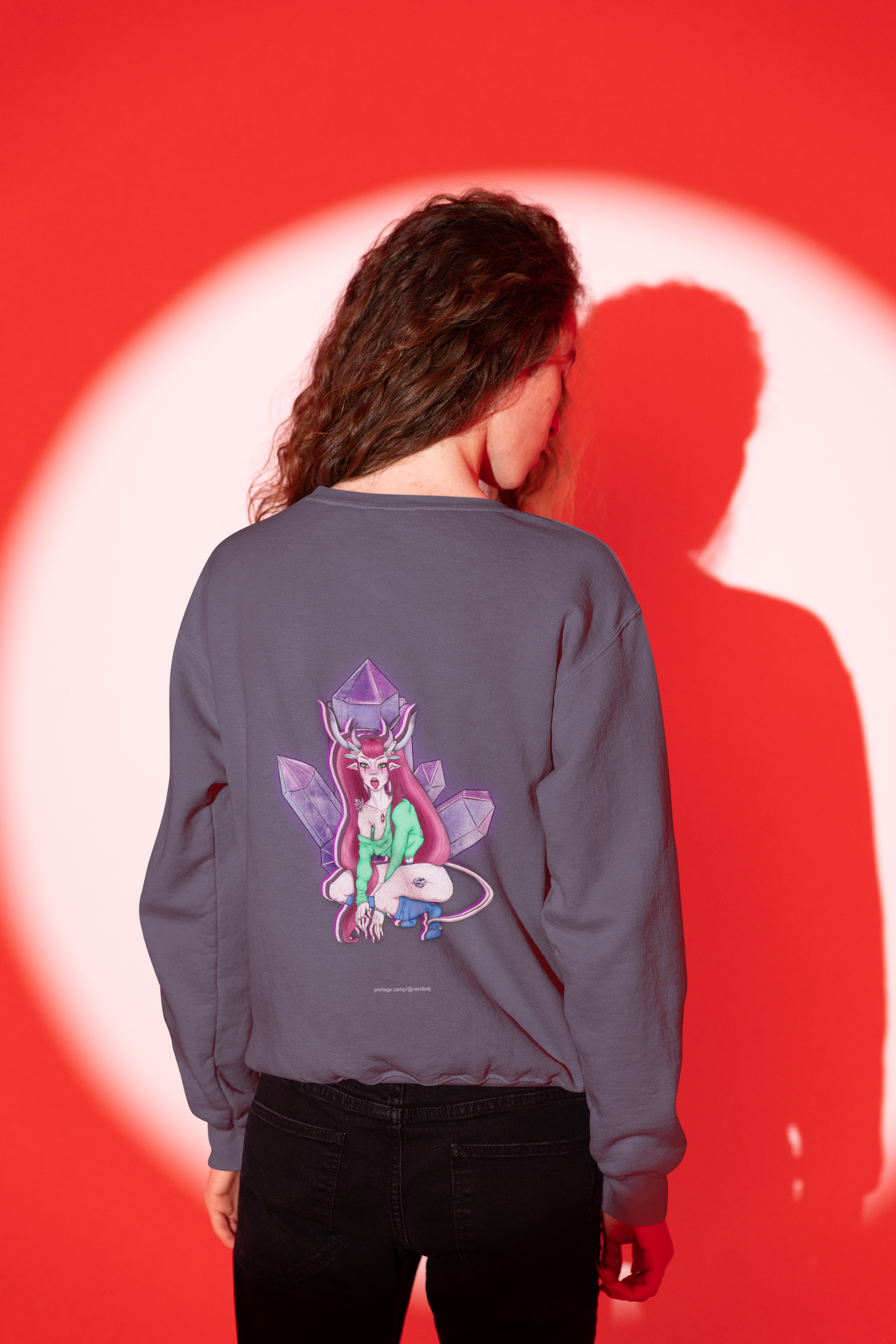 Heart Thief Garment-Dyed Crewneck in Denim, worn by a man seen from behind in a studio, his shadow on the wall behind him, showing the large print on the back. Digital product mockup.