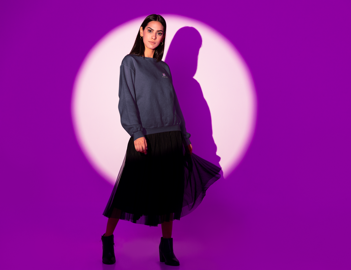 Amethyst After Hours Garment-Dyed Crewneck in True Navy, worn by a woman in a spotlight against purple, with the Amethyst After Hours logo and portage.camp on the chest. Digital product mockup.