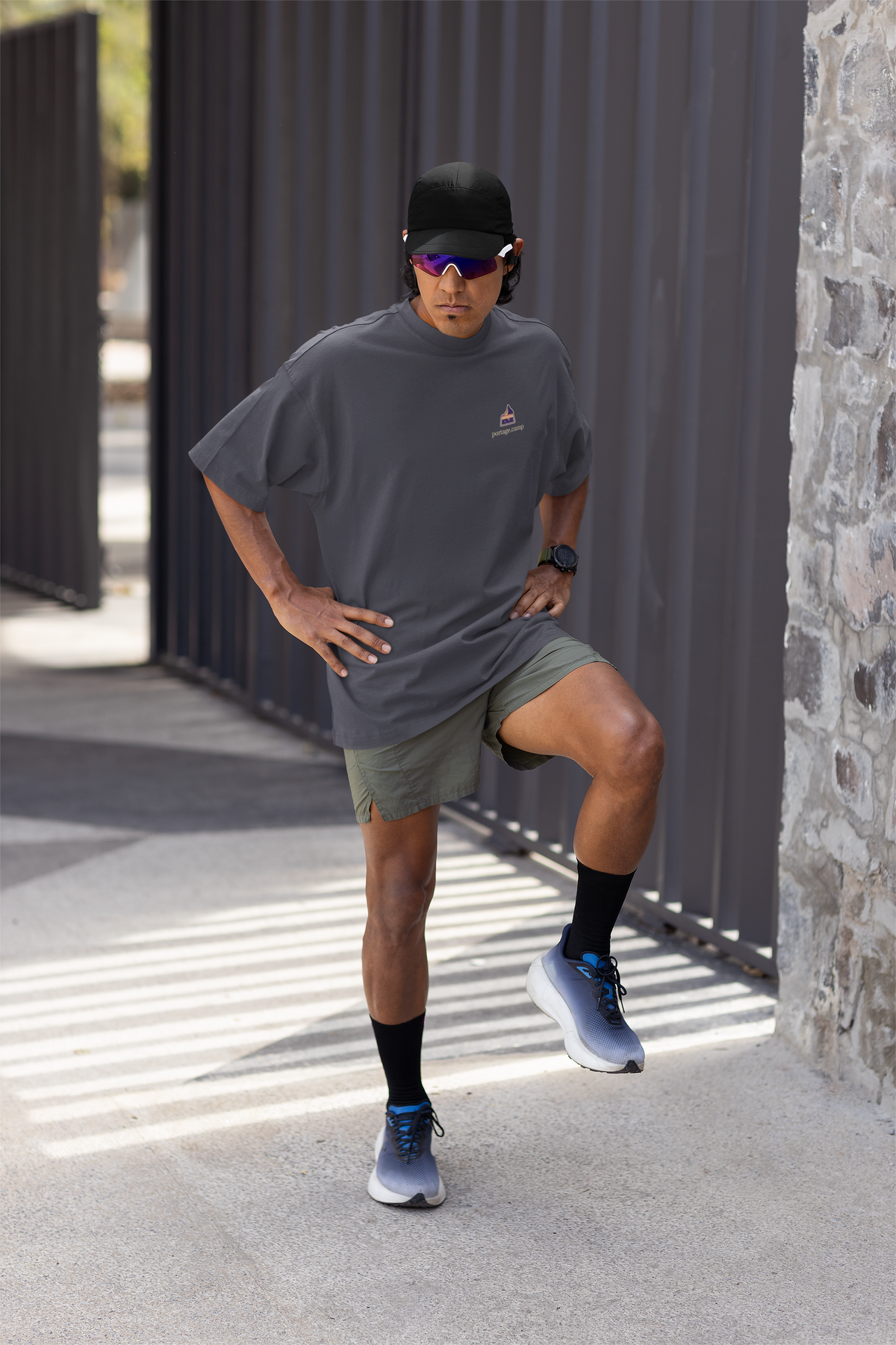 A Different Sky Garment-Dyed Tee in Navy, worn by a man stretching before a run, with the A Different Sky logo and portage.camp on the chest. Digital product mockup.