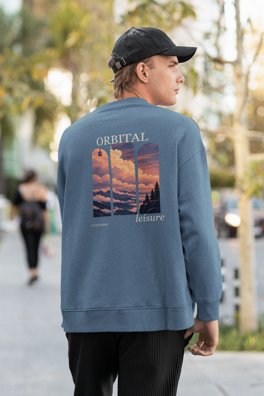 Cloud Ferry Garment-Dyed Crewneck in Blue Jean, worn by a man seen from behind walking down a city street, showing the large print on the back. Digital product mockup.