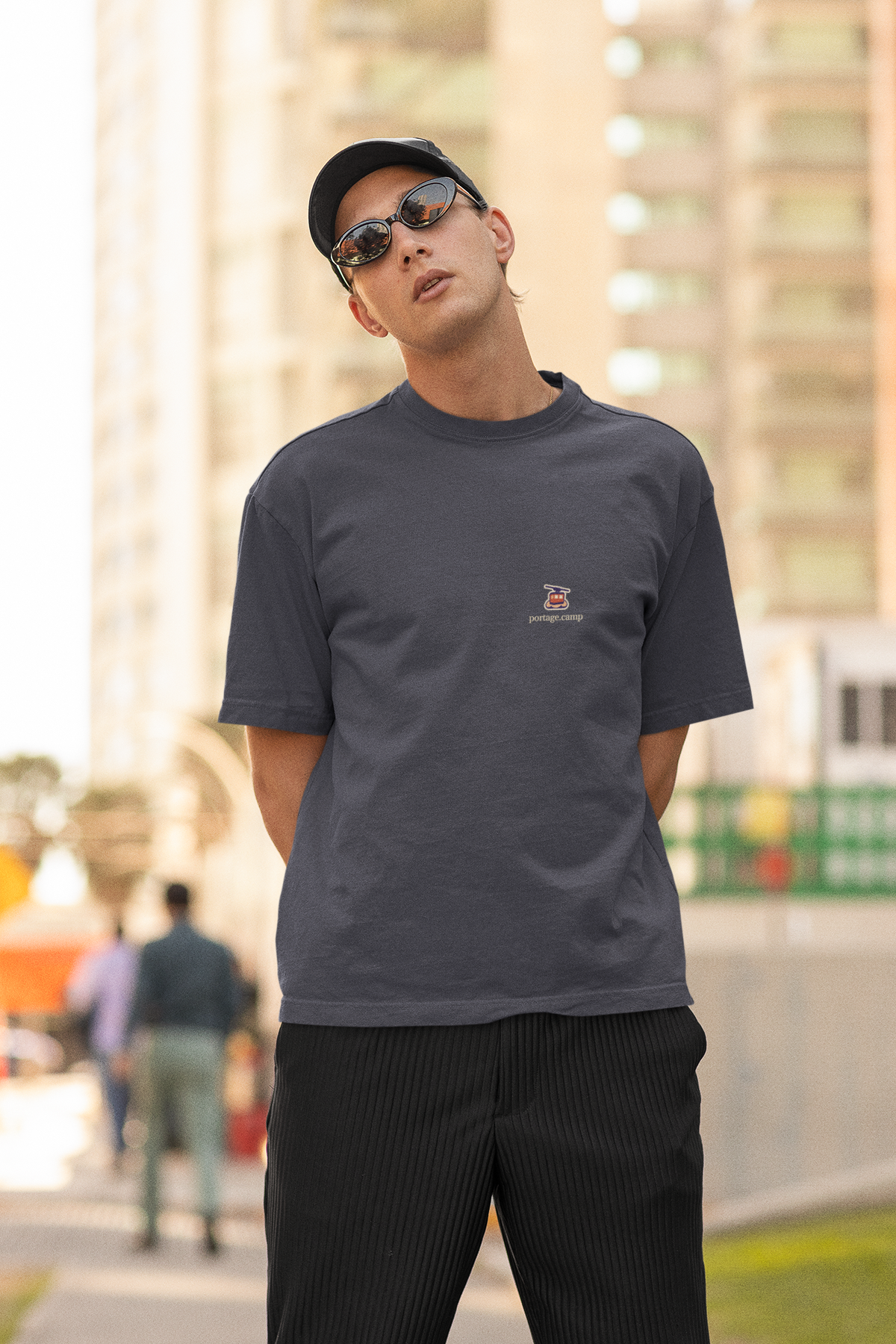 Cloud Ferry Garment-Dyed Tee in Navy, worn by a man in a cap and sunglasses on a city street, with the Cloud Ferry logo and portage.camp on the chest. Digital product mockup.