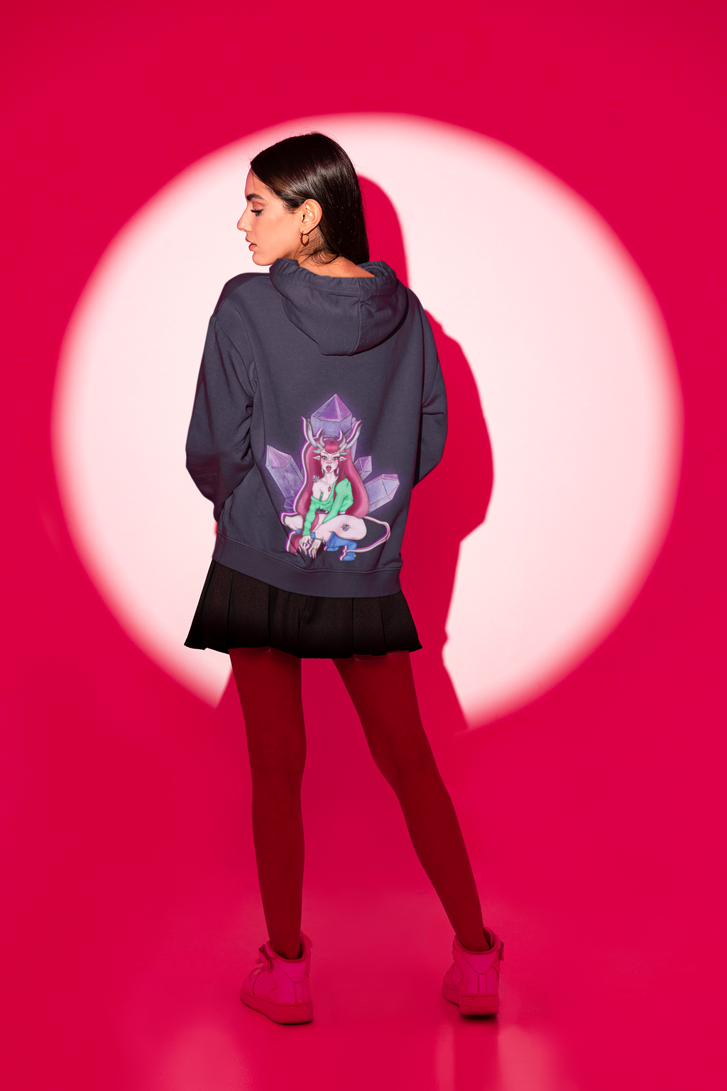 Amethyst After Hours Zip Hoodie in Navy, worn by a woman seen from behind in a studio spotlight, showing the large print on the back. Digital product mockup.