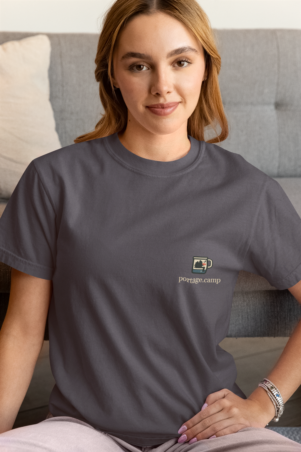 Quiet Hours Garment-Dyed Tee in Navy, worn by a woman at home, with the Quiet Hours logo and portage.camp on the chest. Digital product mockup.