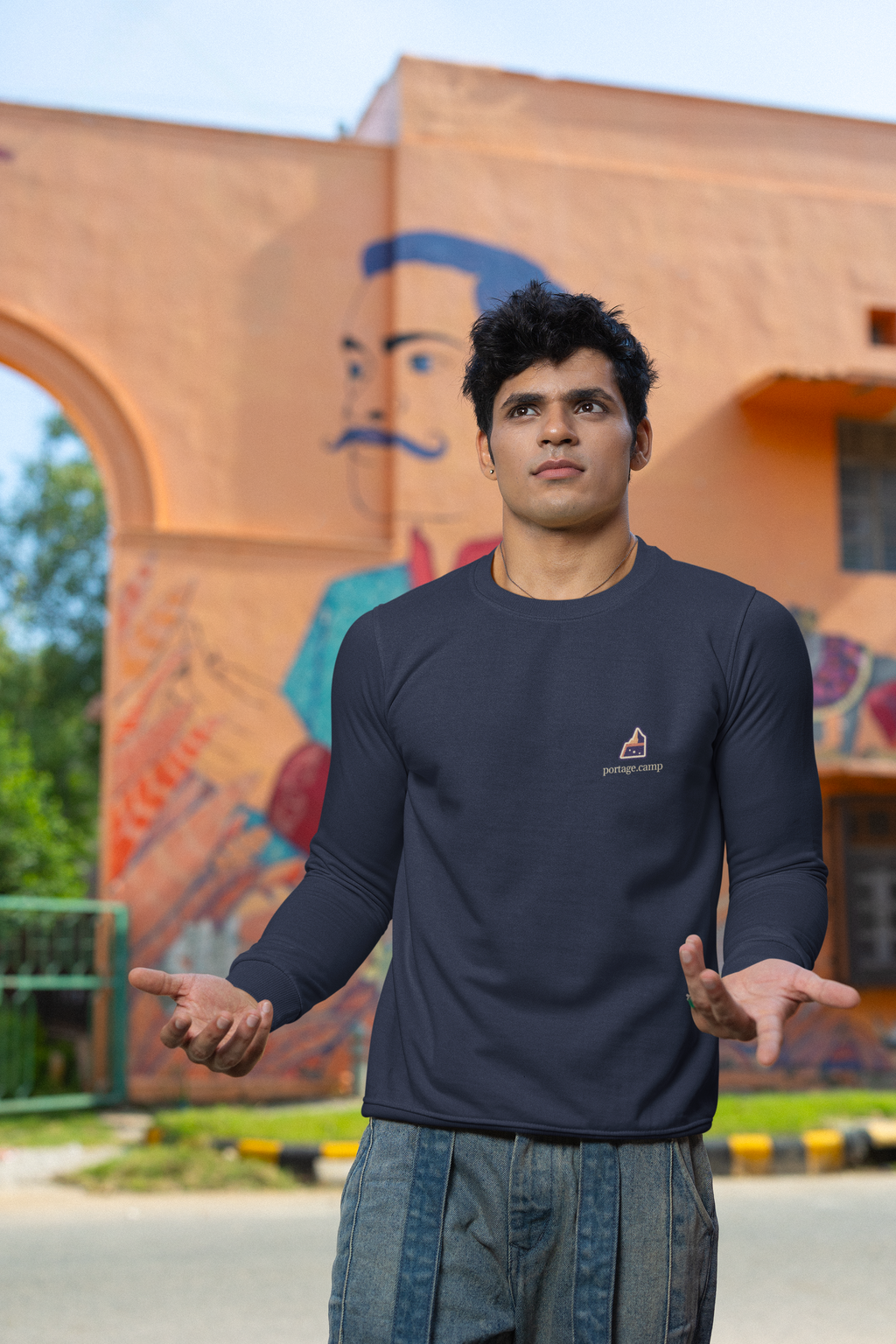 A Different Sky Garment-Dyed Crewneck in True Navy, worn by a man on a city street, with the A Different Sky logo and portage.camp on the chest. Digital product mockup.