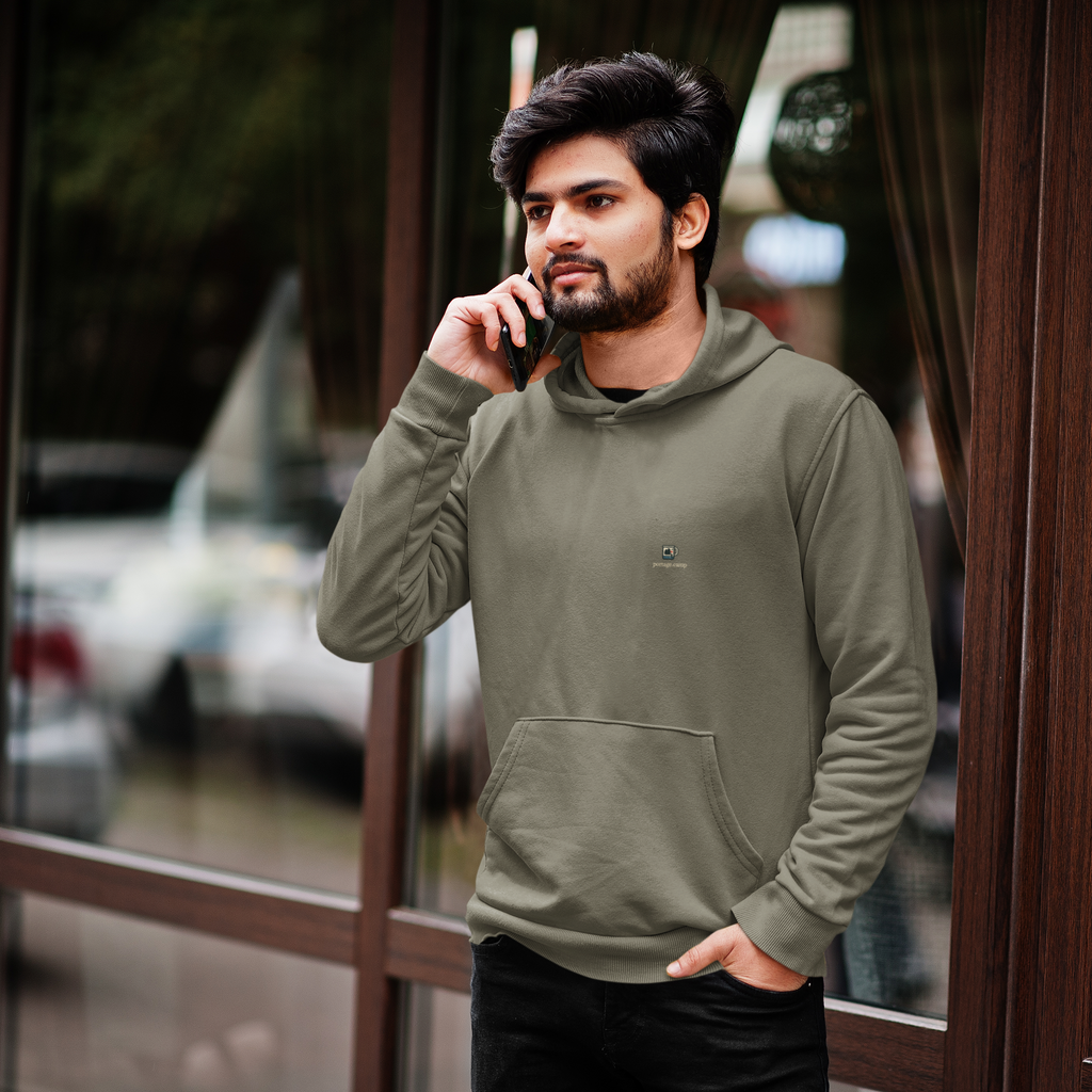 Quiet Hours Heavyweight Hoodie in Olive, worn by a man by a café window, on a phone call, with the Quiet Hours logo and portage.camp on the left chest. Digital product mockup.