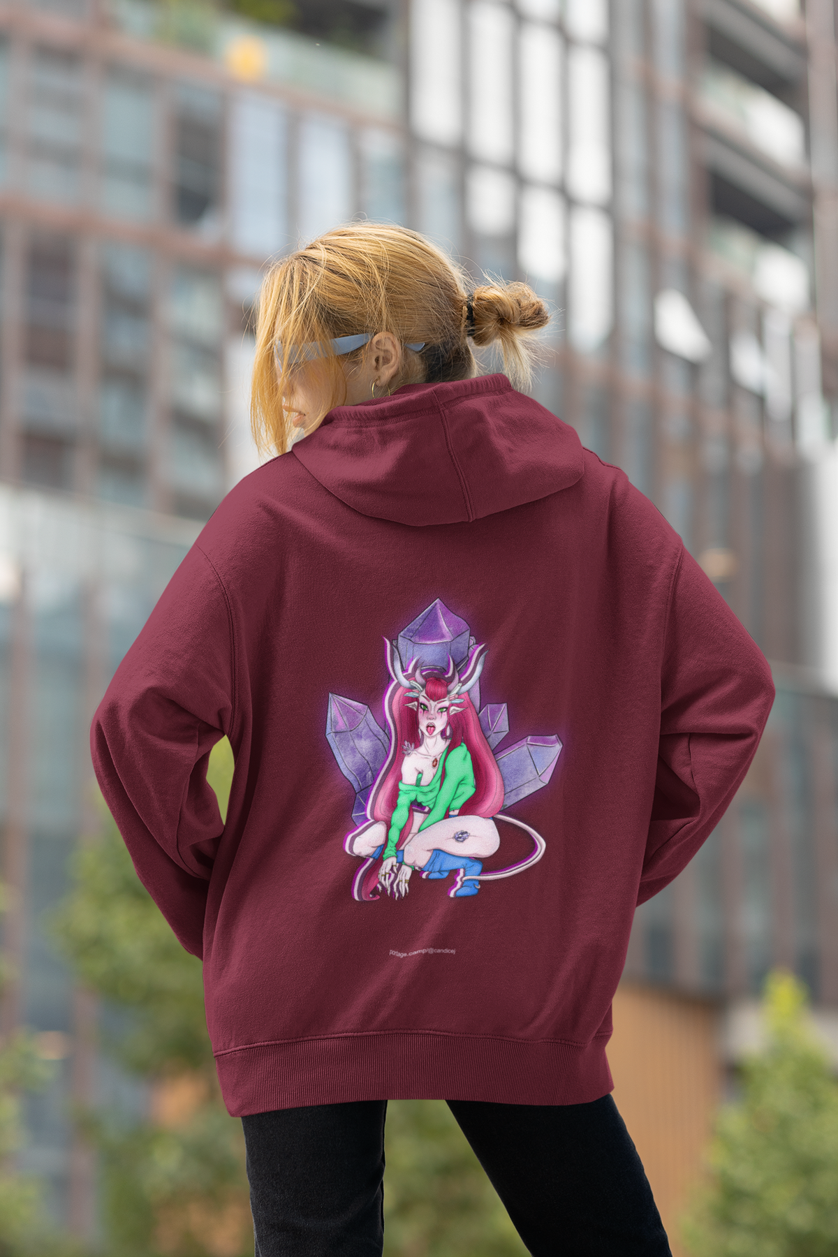Heart Thief Midweight Hoodie in Maroon, worn by a woman seen from behind by tall city buildings, showing the large print on the back. Digital product mockup.