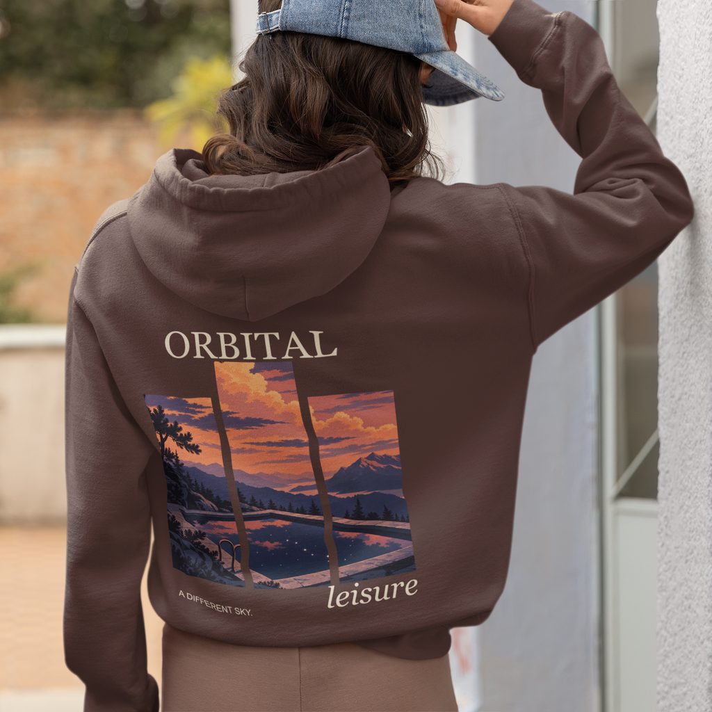 A Different Sky Heavyweight Hoodie in Brown, worn by a woman seen from behind at home, showing the large print on the back. Digital product mockup.