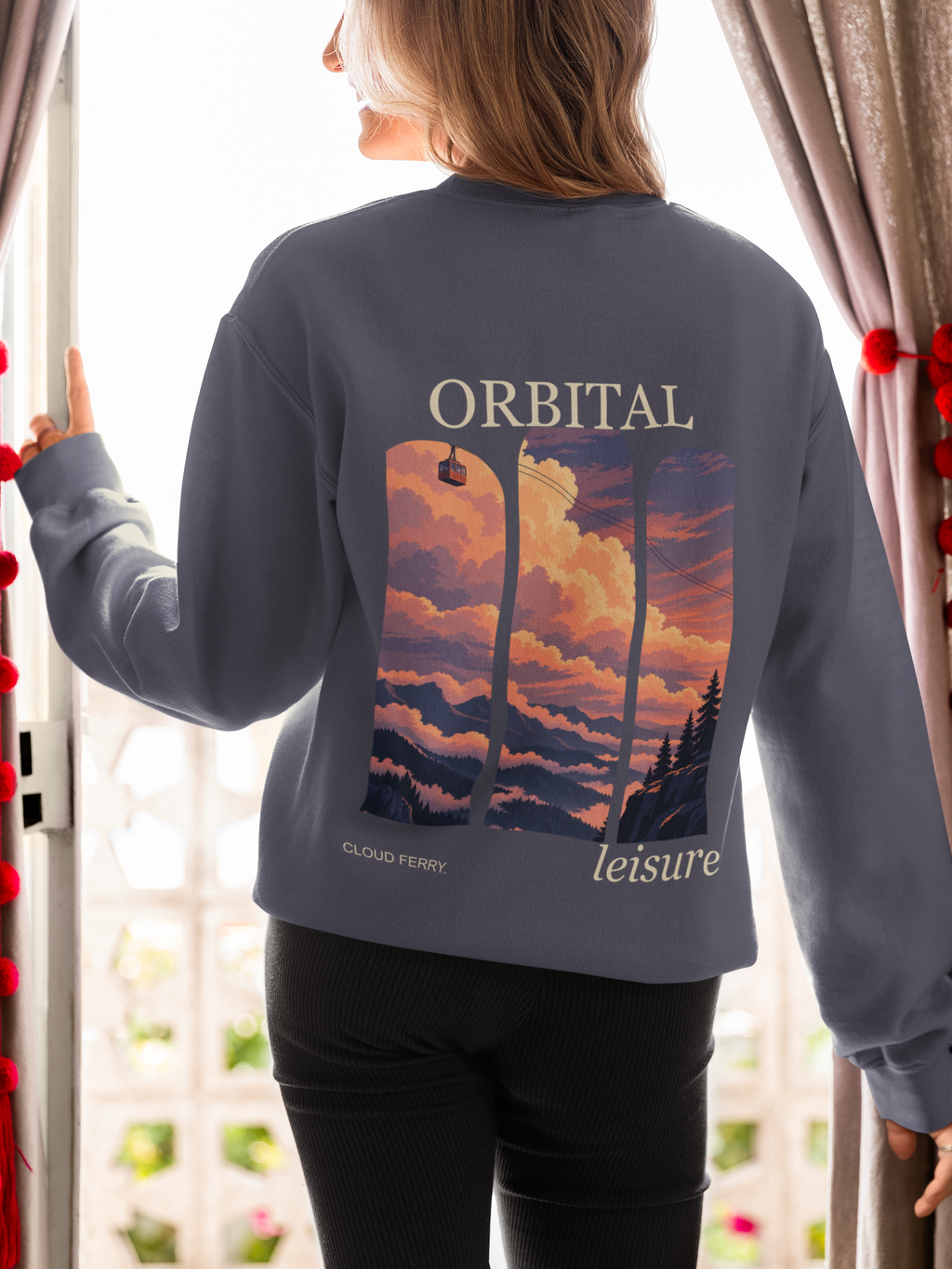 Cloud Ferry Garment-Dyed Crewneck in Denim, worn by a woman seen from behind at an open door, showing the large print on the back. Digital product mockup.