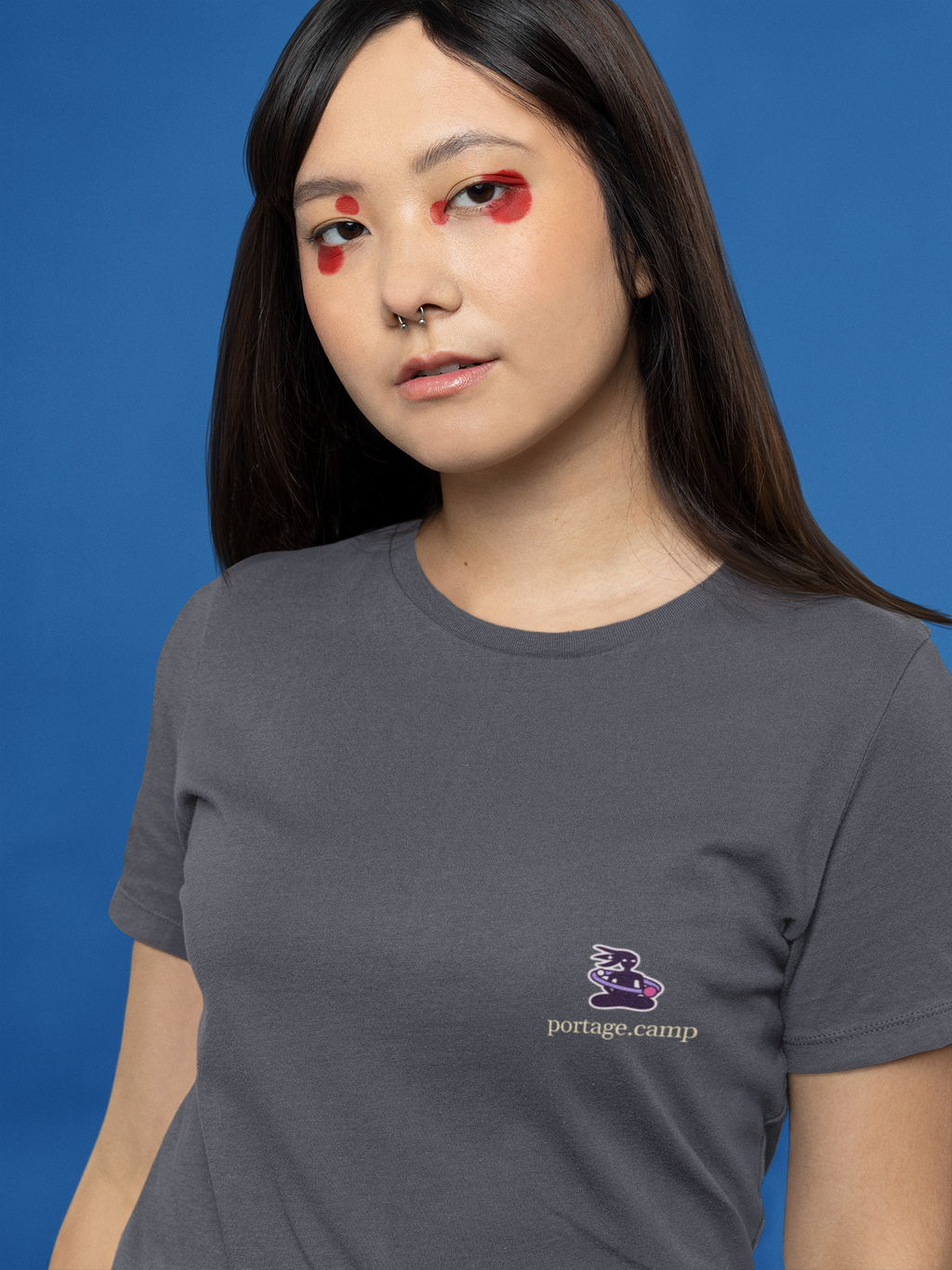 Orbit Keeper Garment-Dyed Tee in Navy, worn by a woman with graphic eyeliner, close up, with the Orbit Keeper logo and portage.camp on the chest. Digital product mockup.
