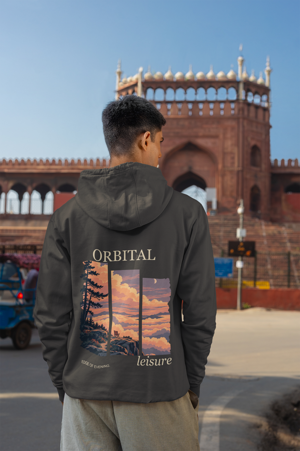 A Different Sky Heavyweight Hoodie in Black, worn by a man seen from behind on a city street, showing the large print on the back. Digital product mockup.