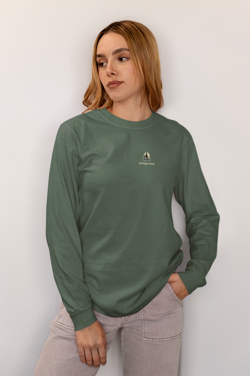 Quiet Hours Garment-Dyed Long-Sleeve Tee in Blue Spruce, worn by a woman at home, with the Quiet Hours logo and portage.camp on the chest. Digital product mockup.