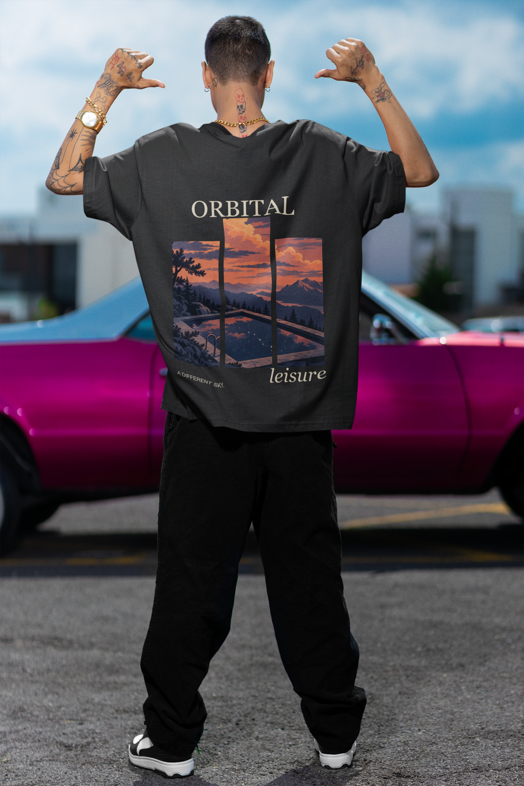 Amethyst After Hours Garment-Dyed Tee in Black, worn by a man seen from behind by a pink car, showing the large print on the back. Digital product mockup.