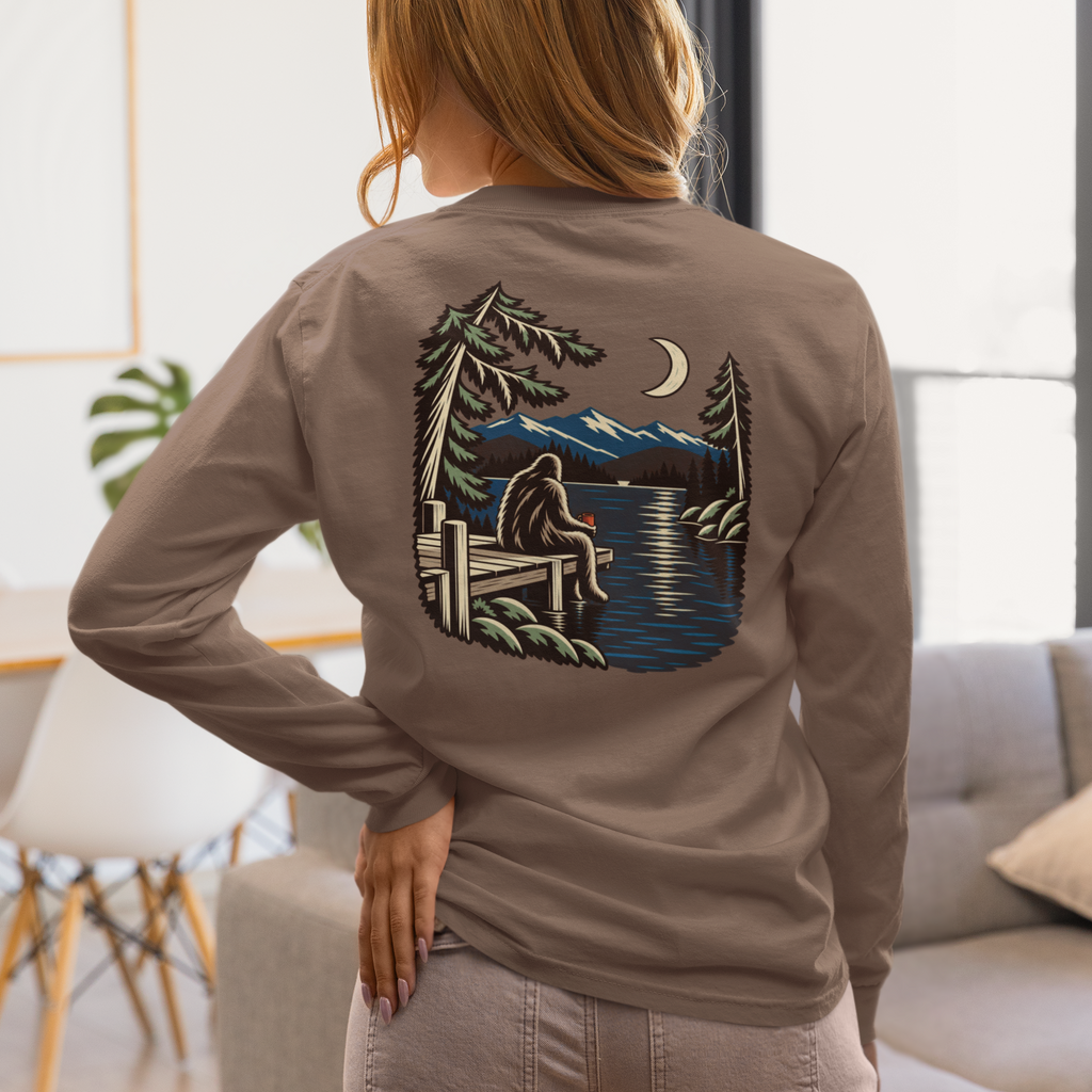 Quiet Hours Garment-Dyed Long-Sleeve Tee in Espresso, worn by a woman seen from behind at home, showing the large print on the back. Digital product mockup.