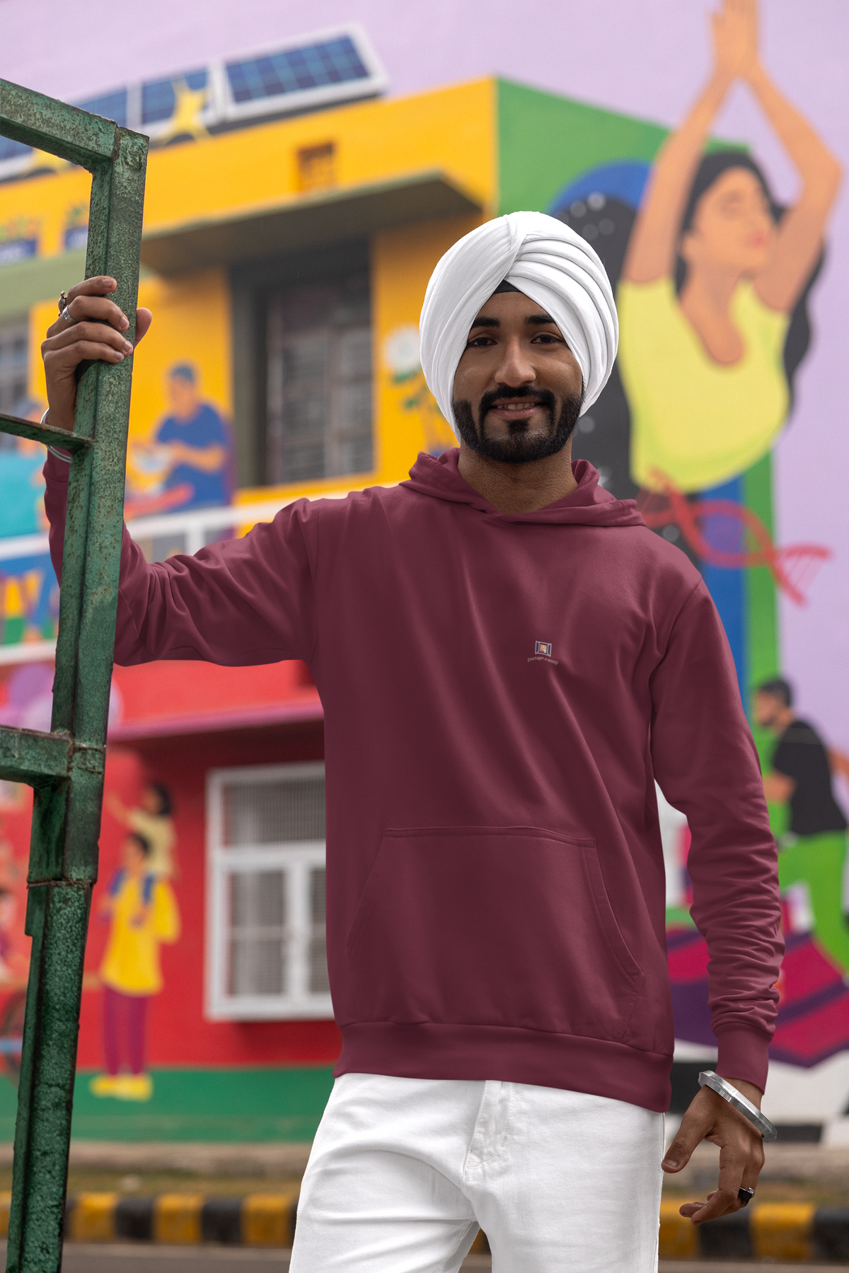 Open Late Midweight Hoodie in Maroon, worn by a man in a turban on a busy street, with the Open Late logo and portage.camp on the chest. Digital product mockup.