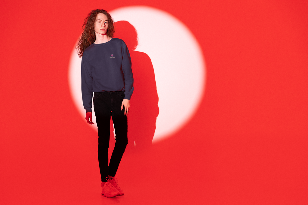 Heart Thief Garment-Dyed Crewneck in True Navy, worn by a man against a red light, with the Heart Thief logo and portage.camp on the chest. Digital product mockup.