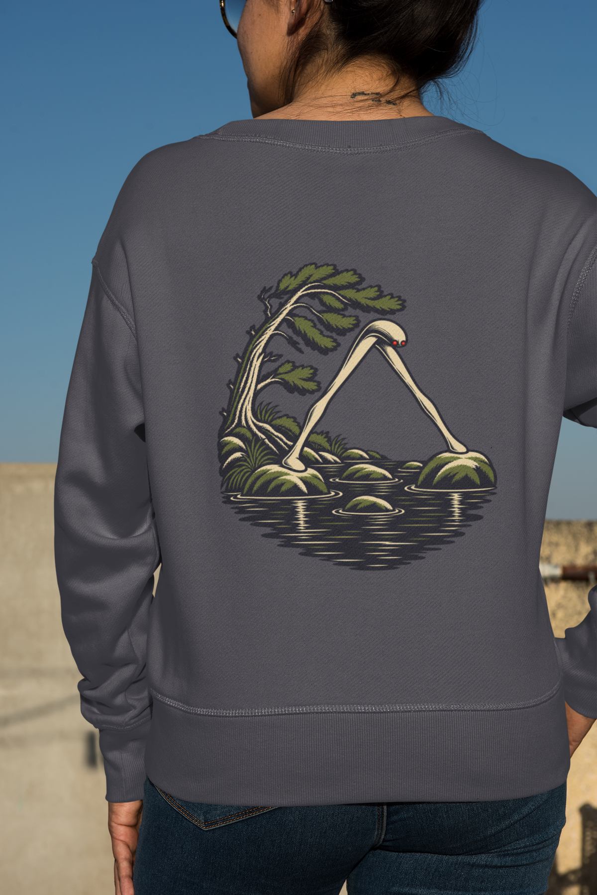 Small Hours Garment-Dyed Crewneck in Denim, worn by a woman seen from behind against a plain backdrop, showing the large print on the back. Digital product mockup.