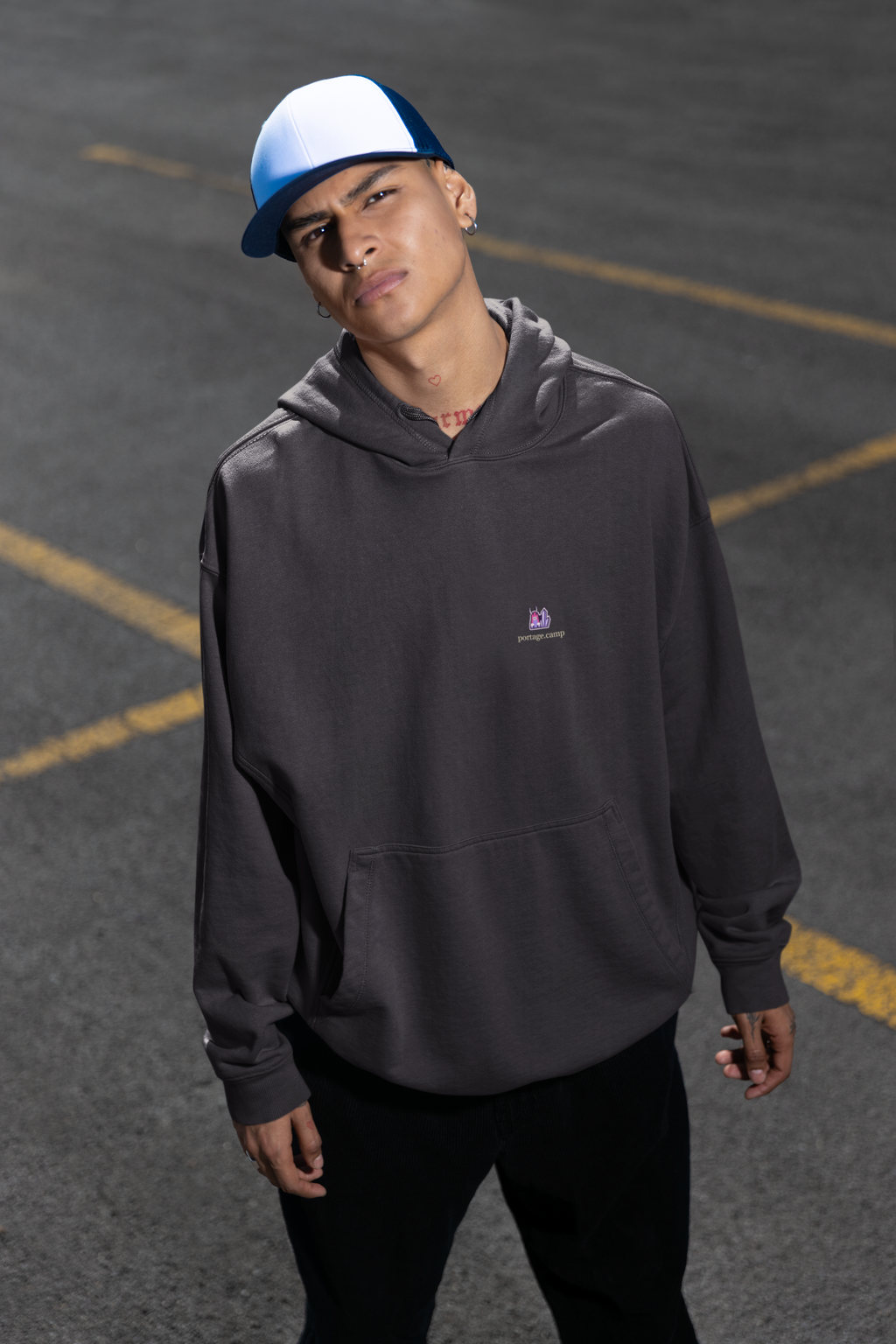 Amethyst After Hours Midweight Hoodie in Black, worn by a man in a parking lot, with the Amethyst After Hours logo and portage.camp on the chest. Digital product mockup.