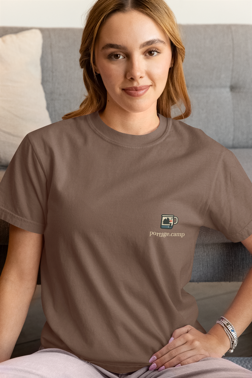 Quiet Hours Garment-Dyed Tee in Espresso, worn by a woman at home, with the Quiet Hours logo and portage.camp on the chest. Digital product mockup.