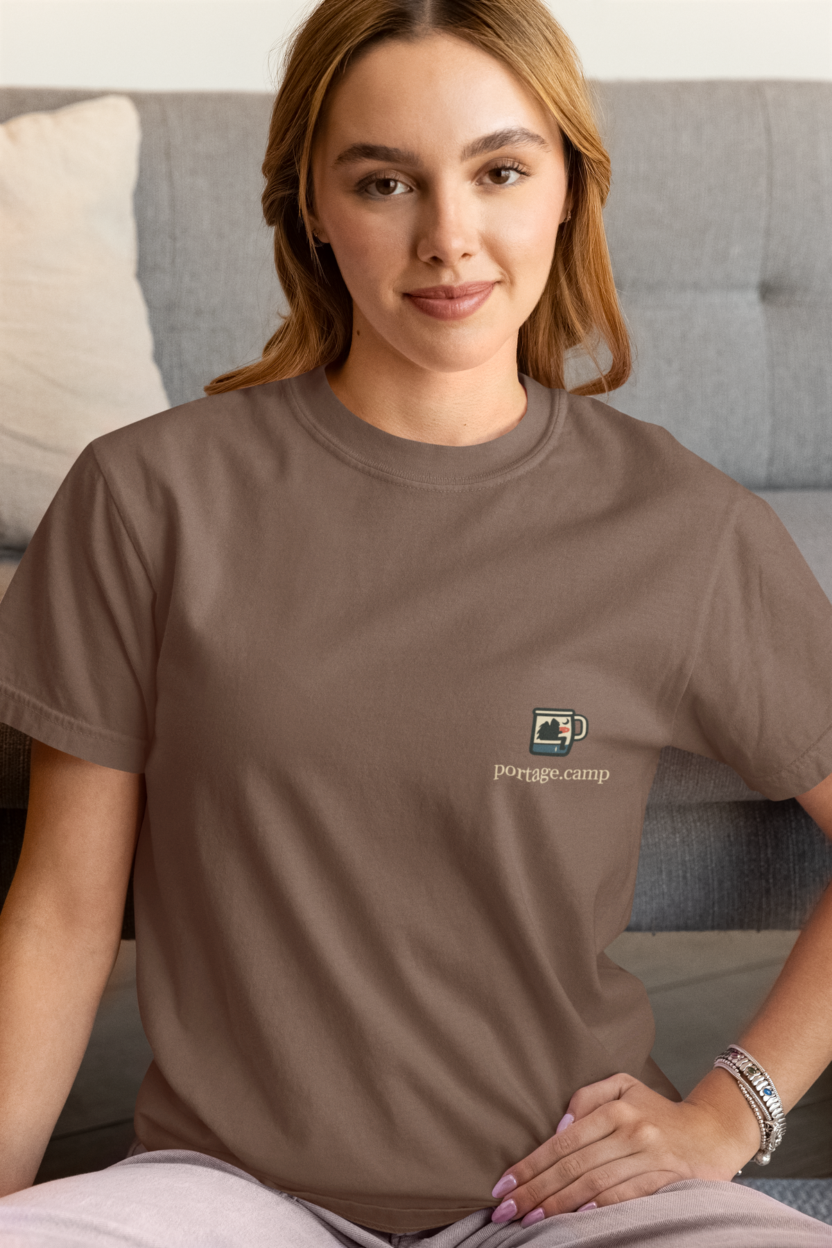 Quiet Hours Garment-Dyed Tee in Espresso, worn by a woman at home, with the Quiet Hours logo and portage.camp on the chest. Digital product mockup.