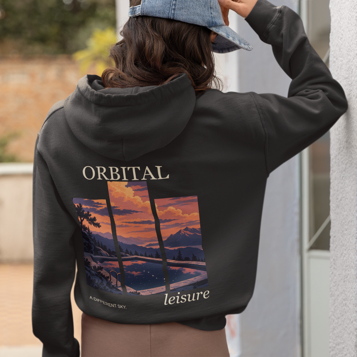 A Different Sky Zip Hoodie in Black, worn by a woman seen from behind at home, showing the large print on the back. Digital product mockup.