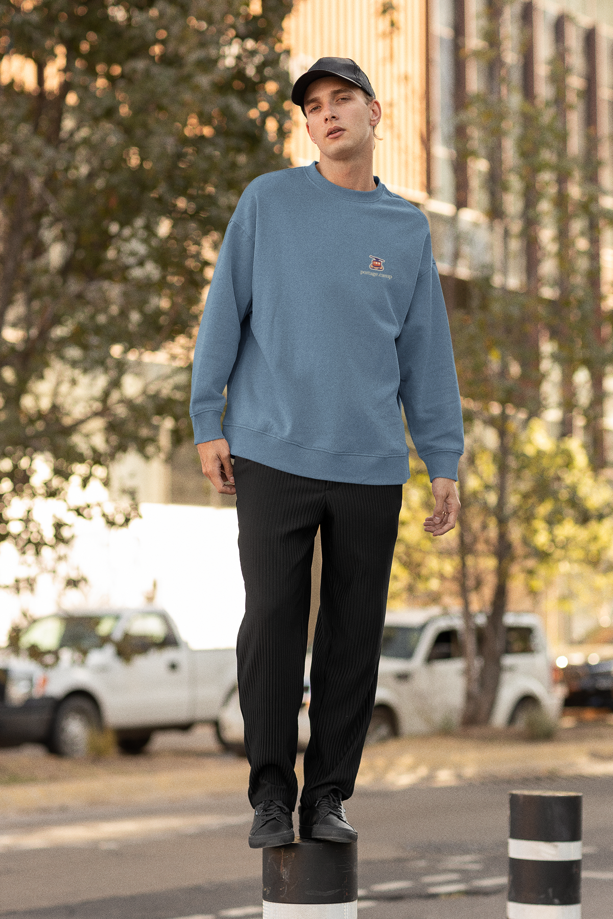 Cloud Ferry Garment-Dyed Crewneck in Blue Jean, worn by a man on a city street, with the Cloud Ferry logo and portage.camp on the chest. Digital product mockup.