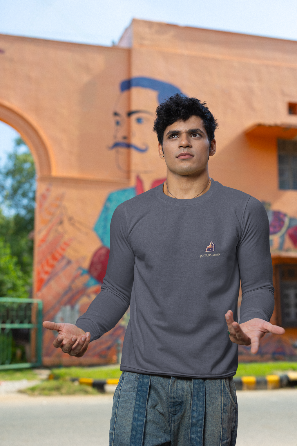 A Different Sky Garment-Dyed Crewneck in Denim, worn by a man on a city street, with the A Different Sky logo and portage.camp on the chest. Digital product mockup.