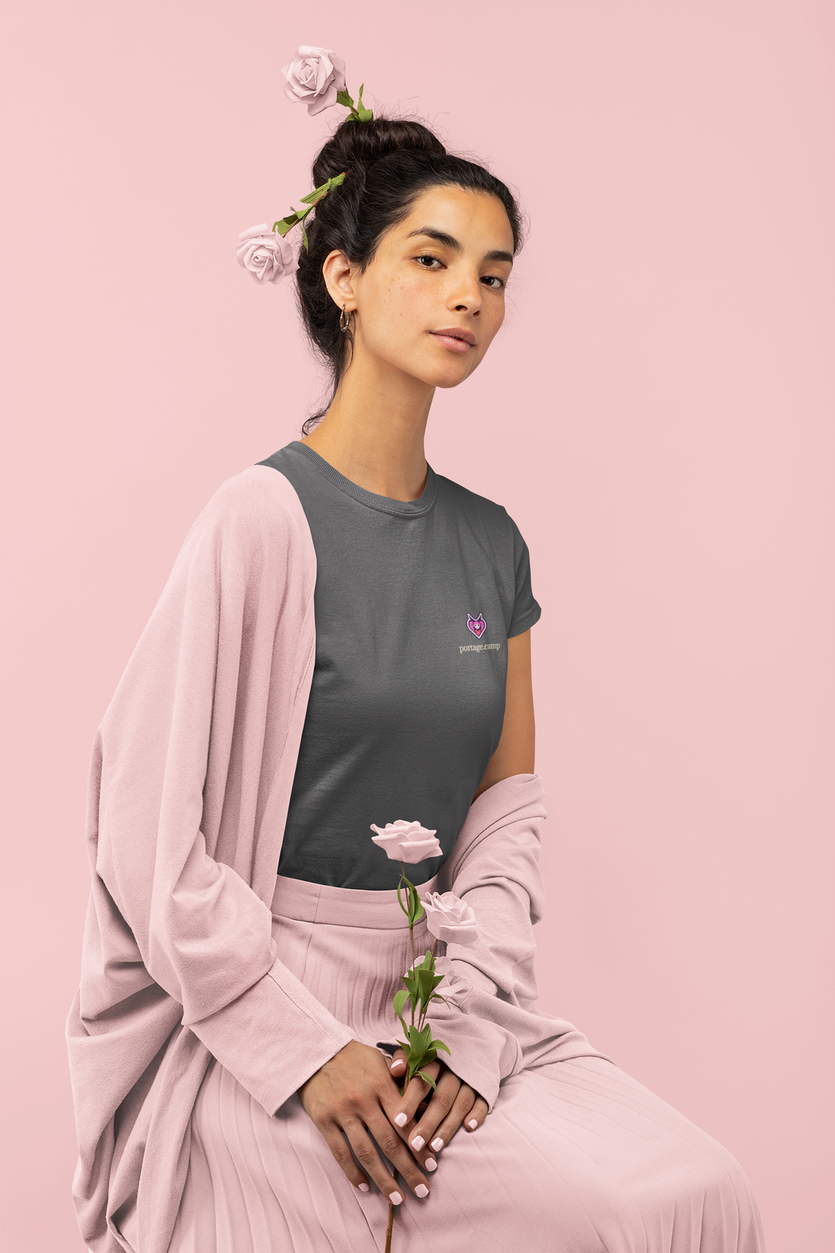 Heart Thief Garment-Dyed Tee in Graphite, worn by a woman holding a rose, with the Heart Thief logo and portage.camp on the chest. Digital product mockup.