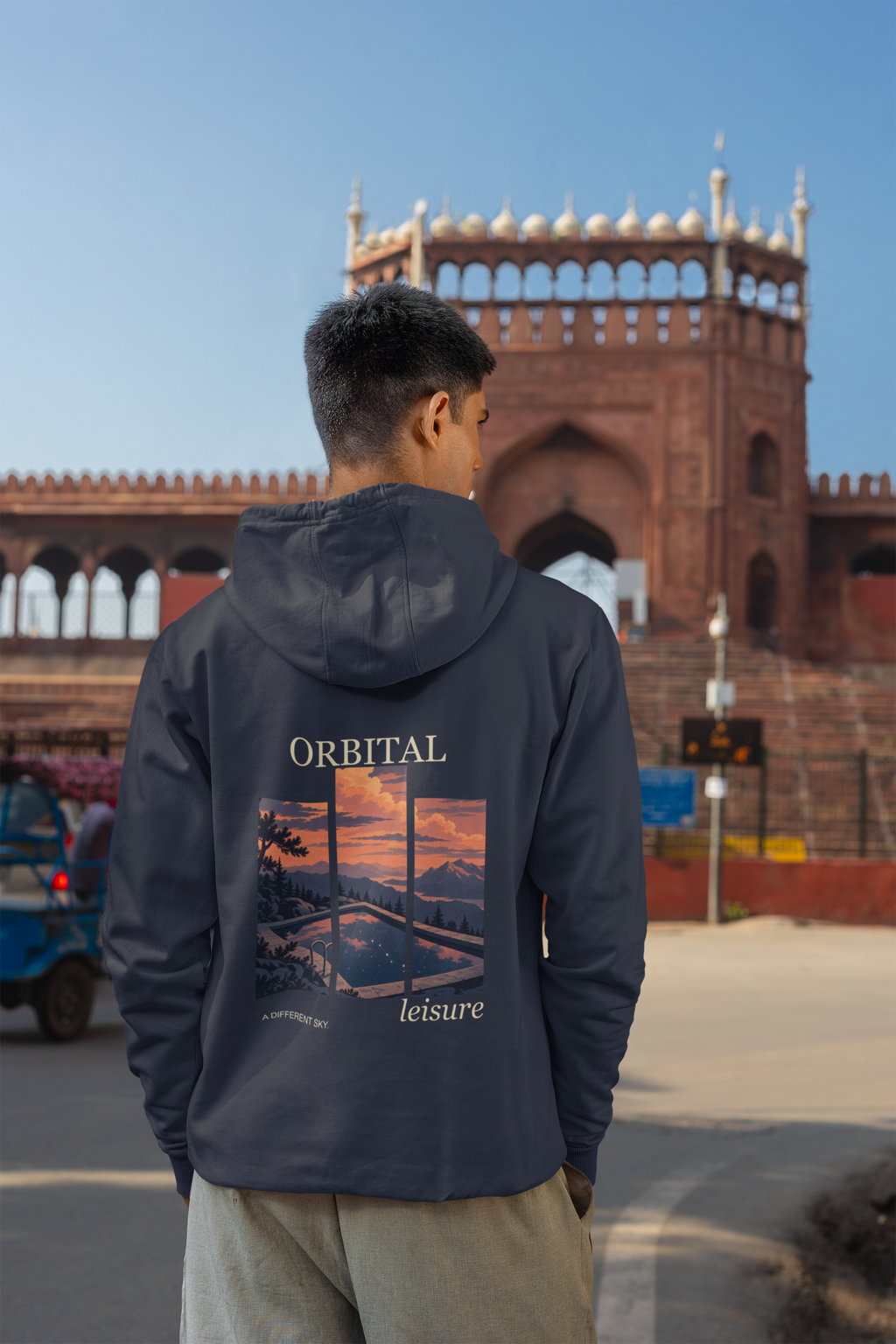 A Different Sky Zip Hoodie in Navy, worn by a man seen from behind on a city street, showing the large print on the back. Digital product mockup.