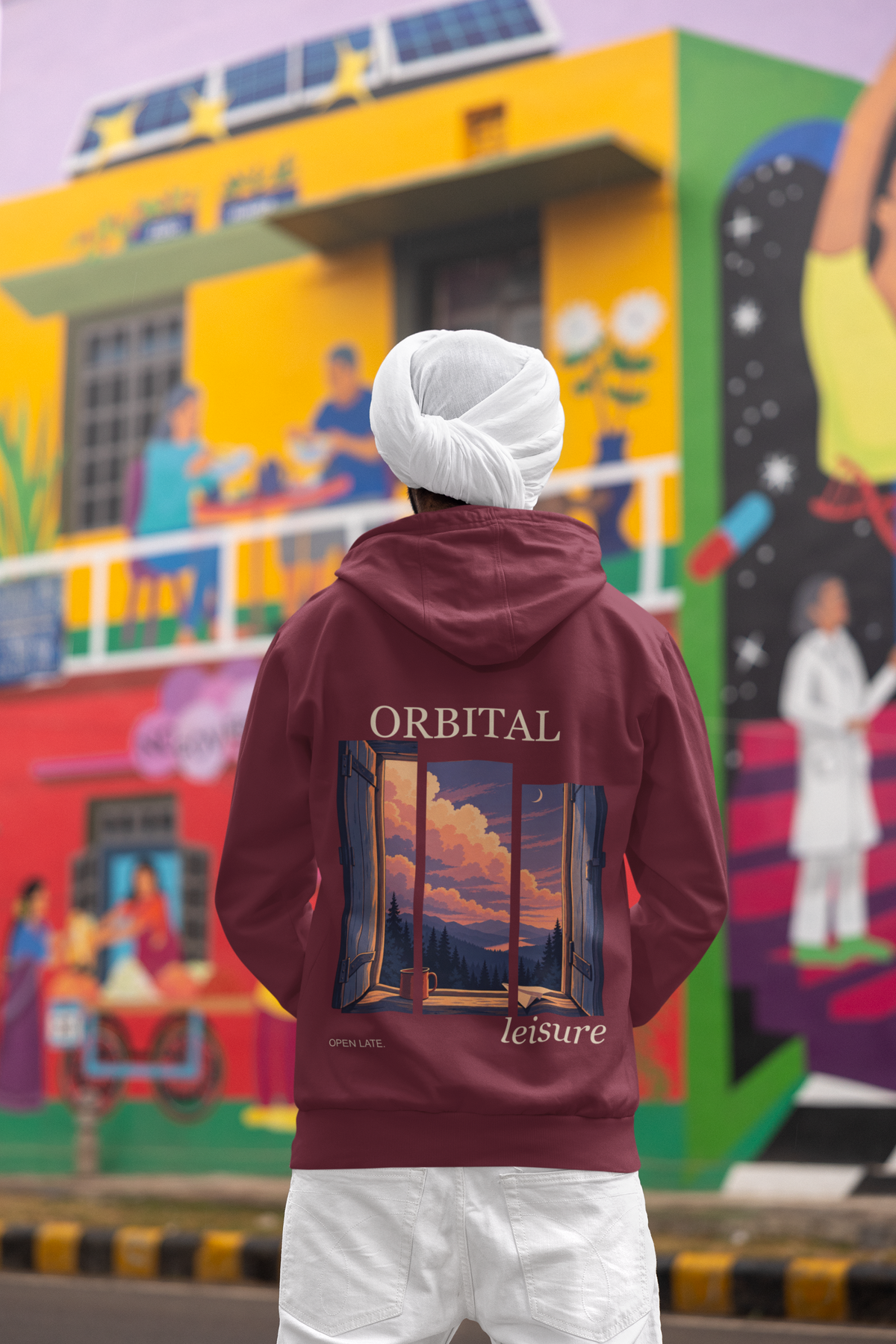 Open Late Midweight Hoodie in Maroon, worn by a man seen from behind in a turban by a painted mural, showing the large print on the back. Digital product mockup.