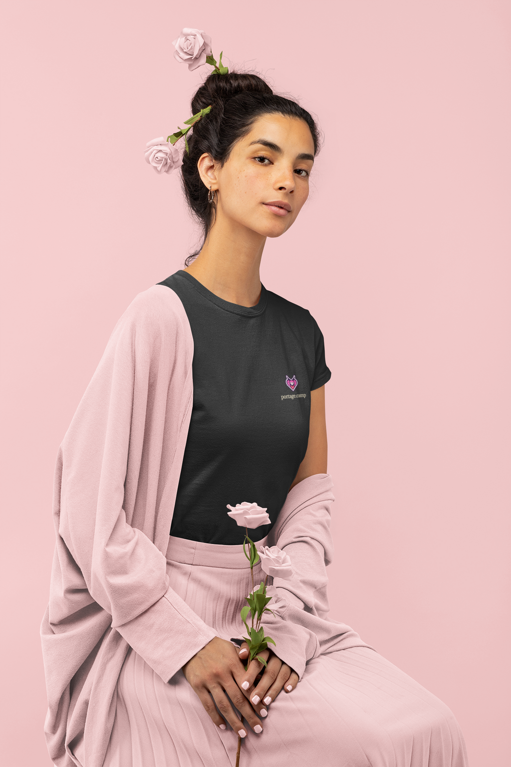 Heart Thief Garment-Dyed Tee in Black, worn by a woman holding a rose, with the Heart Thief logo and portage.camp on the chest. Digital product mockup.