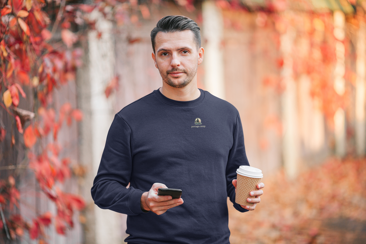 Quiet Hours Garment-Dyed Crewneck in True Navy, worn by a man among autumn leaves, with the Quiet Hours logo and portage.camp on the chest. Digital product mockup.