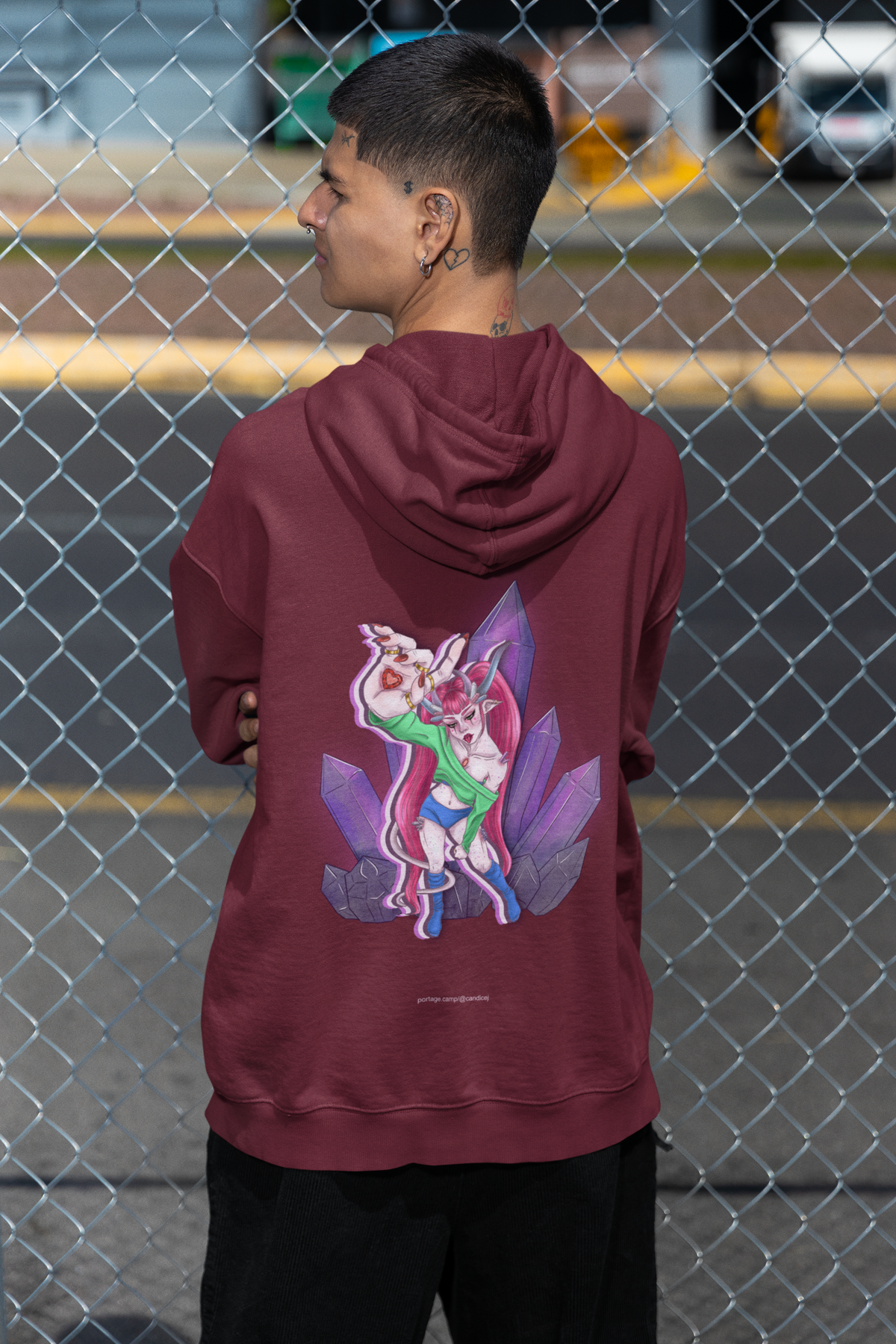 Amethyst After Hours Midweight Hoodie in Maroon, worn by a man seen from behind by a chain-link fence, showing the large print on the back. Digital product mockup.