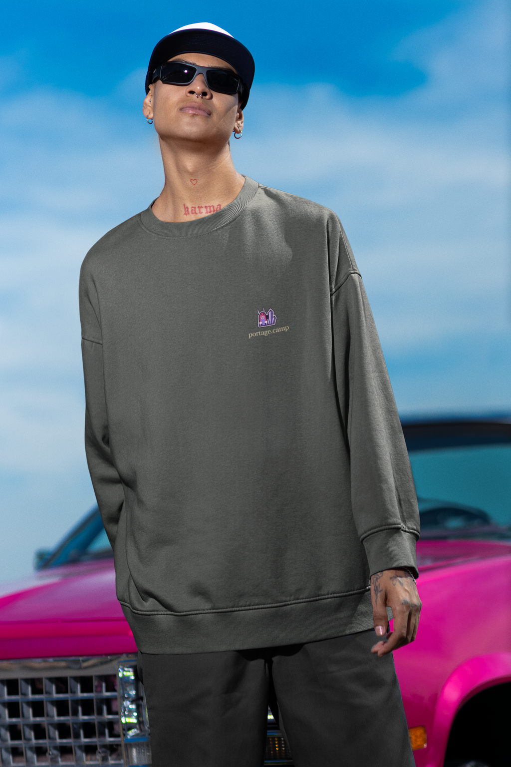 Amethyst After Hours Garment-Dyed Crewneck in Pepper, worn by a man leaning against a car, with the Amethyst After Hours logo and portage.camp on the chest. Digital product mockup.