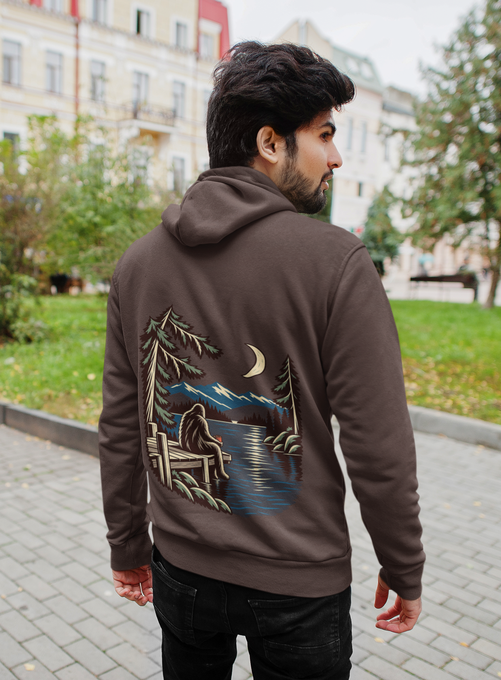 Quiet Hours Heavyweight Hoodie in Brown, worn by a man seen from behind on a quiet city street, showing the large print on the back. Digital product mockup.