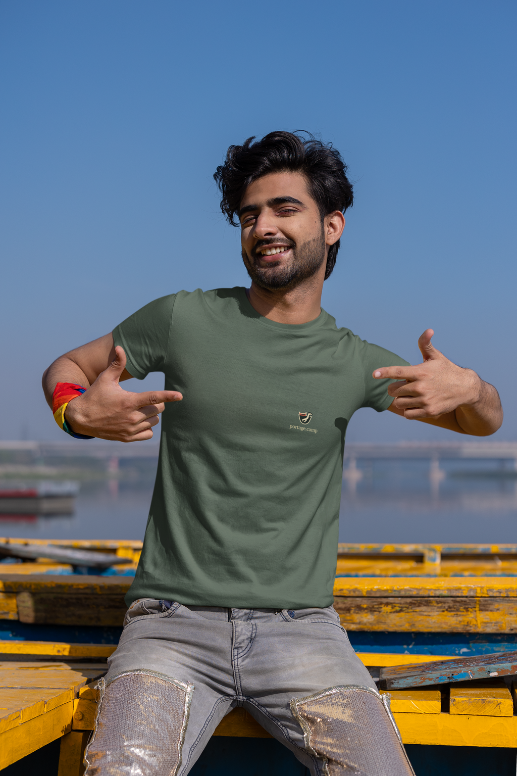 Seen Briefly Garment-Dyed Tee in Blue Spruce, worn by a man on a city street, with the Seen Briefly logo and portage.camp on the chest. Digital product mockup.