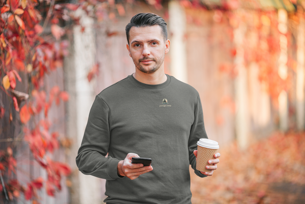 Quiet Hours Garment-Dyed Crewneck in Pepper, worn by a man among autumn leaves, with the Quiet Hours logo and portage.camp on the chest. Digital product mockup.