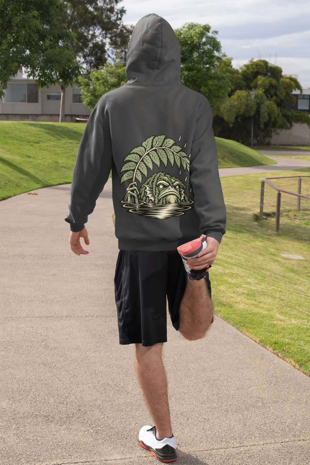 Seen Briefly Heavyweight Hoodie in Black, worn by a man seen from behind on a sunny path, ready for a run, showing the large print on the back. Digital product mockup.