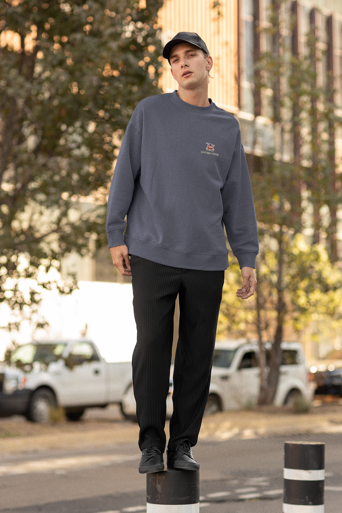Cloud Ferry Garment-Dyed Crewneck in Denim, worn by a man on a city street, with the Cloud Ferry logo and portage.camp on the chest. Digital product mockup.