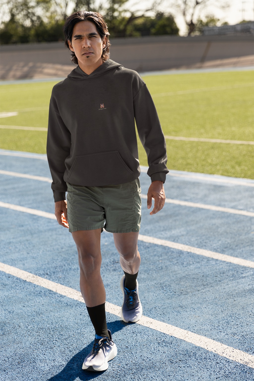 Edge of Evening Midweight Hoodie in Black, worn by a man on a running track, with the Edge of Evening logo and portage.camp on the chest. Digital product mockup.
