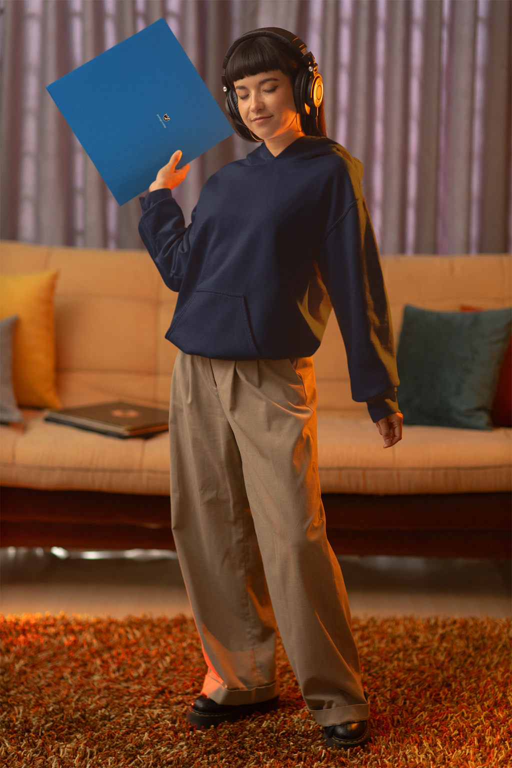 Seen Briefly Midweight Hoodie in Classic Navy, worn by a woman in headphones, holding a record sleeve, with the Seen Briefly logo and portage.camp on the chest. Digital product mockup.