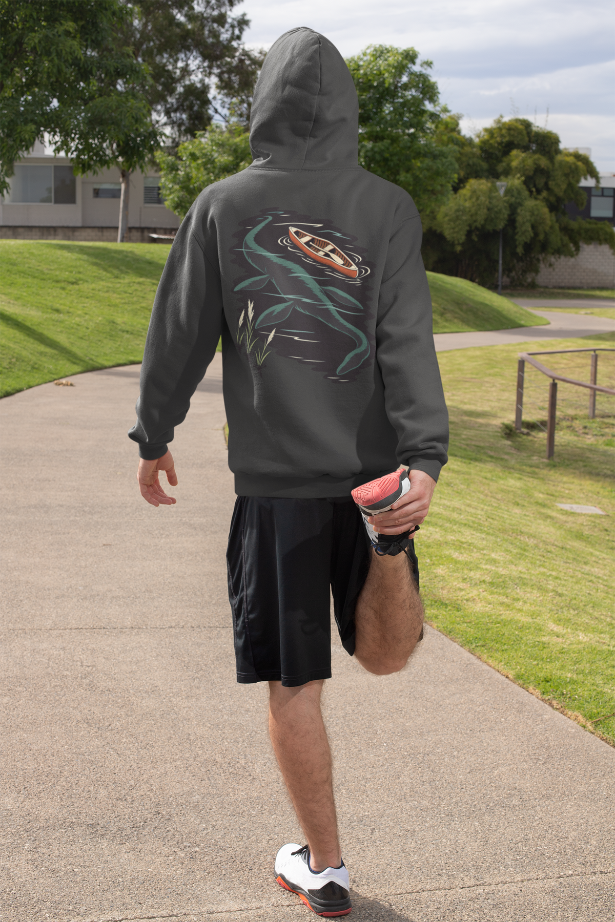 Seen Briefly Heavyweight Hoodie in Black, worn by a man seen from behind on a sunny path, ready for a run, showing the large print on the back. Digital product mockup.