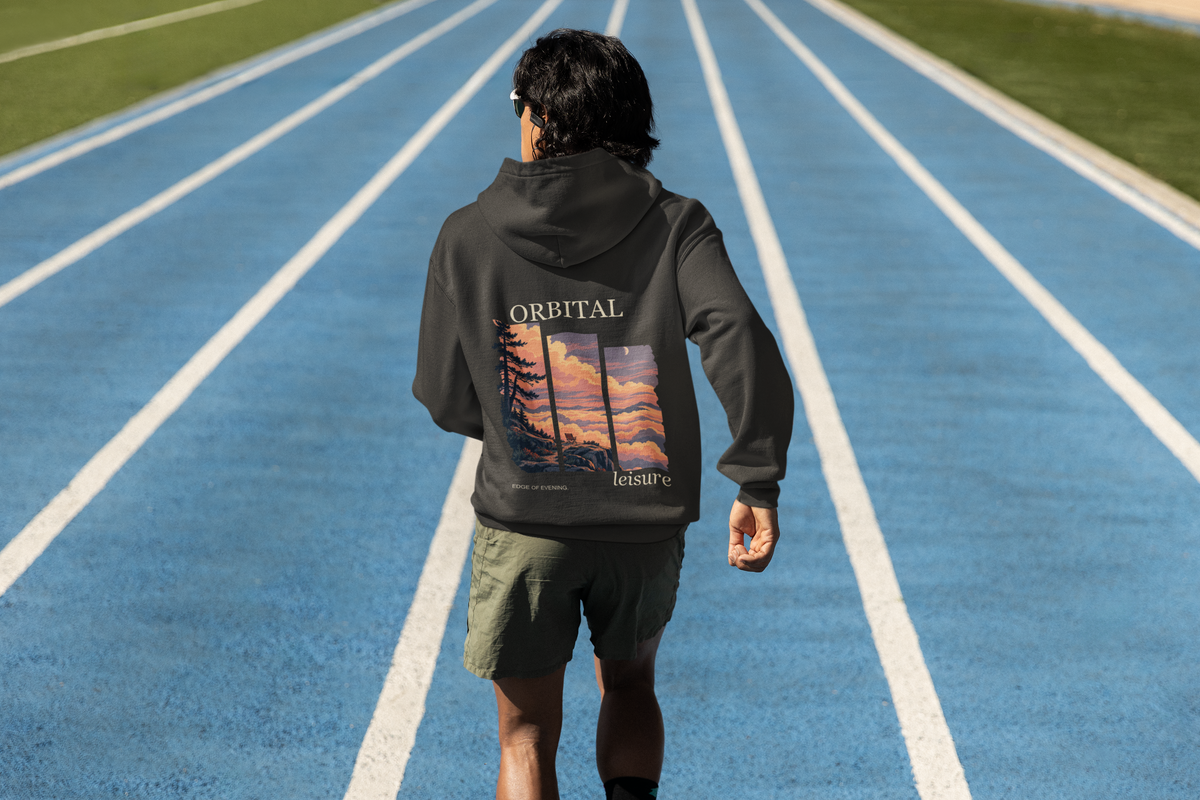 Edge of Evening Zip Hoodie in Black, worn by a man seen from behind on a running track, showing the large print on the back. Digital product mockup.