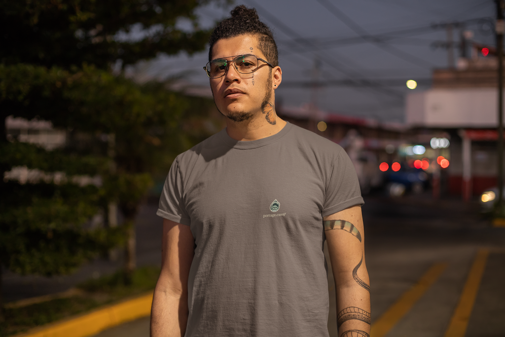 Rain Check Garment-Dyed Tee in Espresso, worn by a man on a street at dusk, with the Rain Check logo and portage.camp on the chest. Digital product mockup.