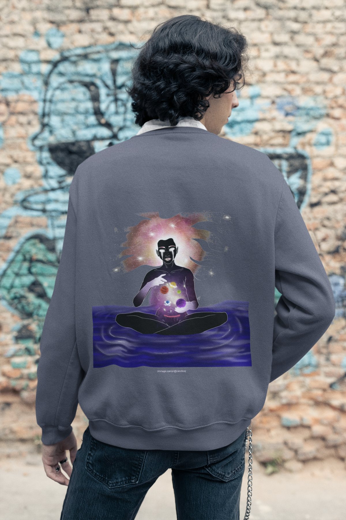 Orbit Keeper Garment-Dyed Crewneck in Denim, worn by a man seen from behind in a studio, showing the large print on the back. Digital product mockup.