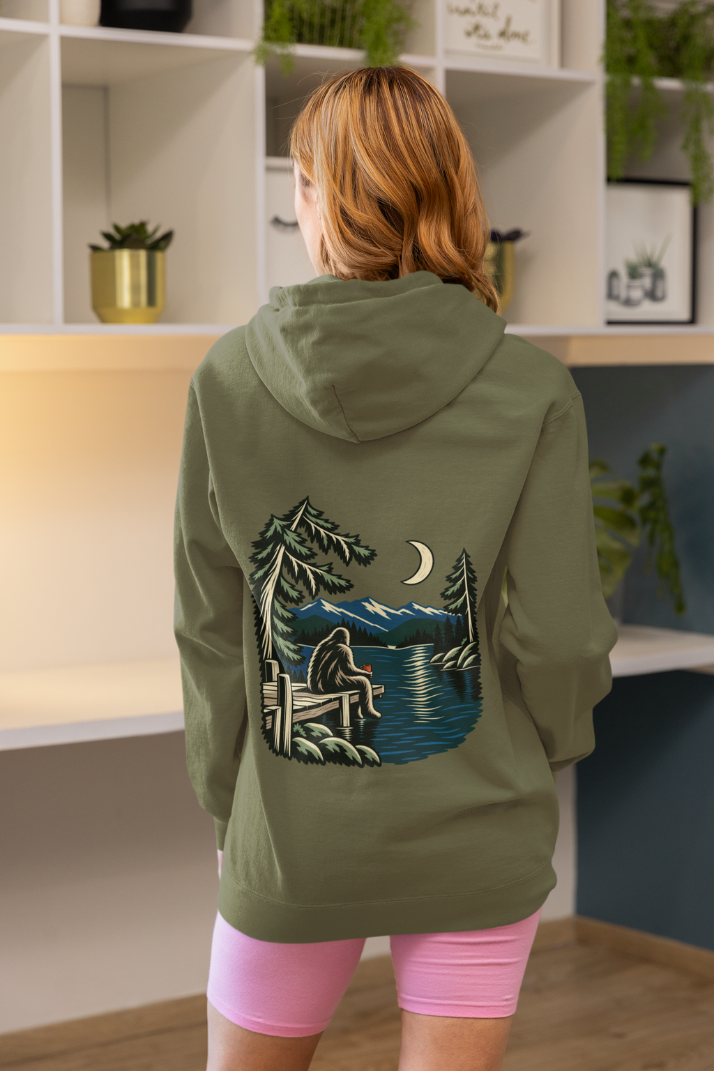 Quiet Hours Zip Hoodie in Military Green, worn by a woman seen from behind at home, showing the large print on the back. Digital product mockup.